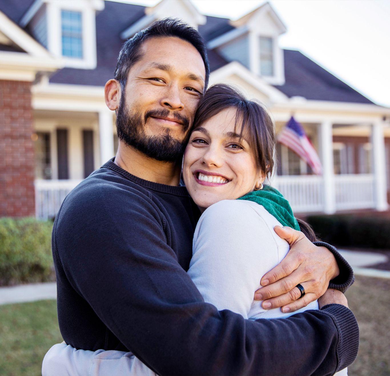 Couple hugging outside of house