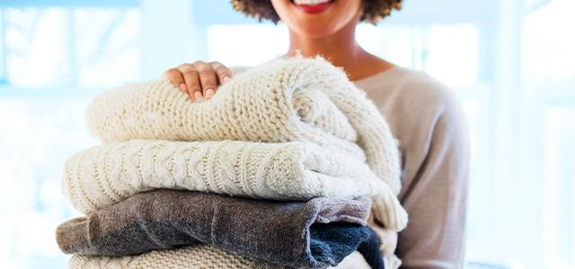 A woman carries a stack of blankets