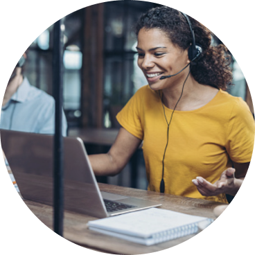 smiling woman on headset sitting at a laptop