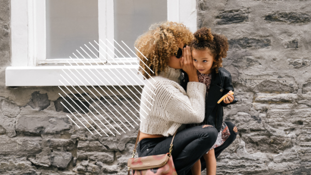 Mother whispering secret to little girl