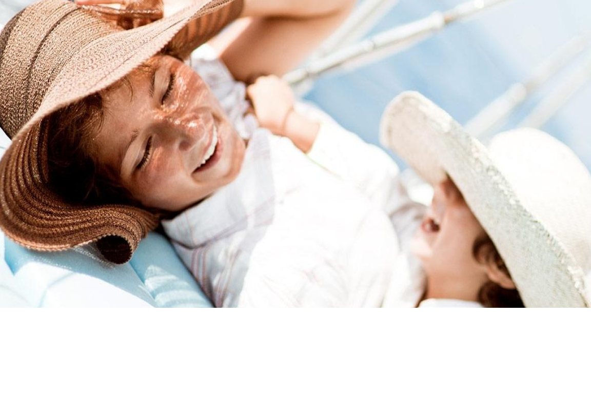 Family with sun hats laughing by the water